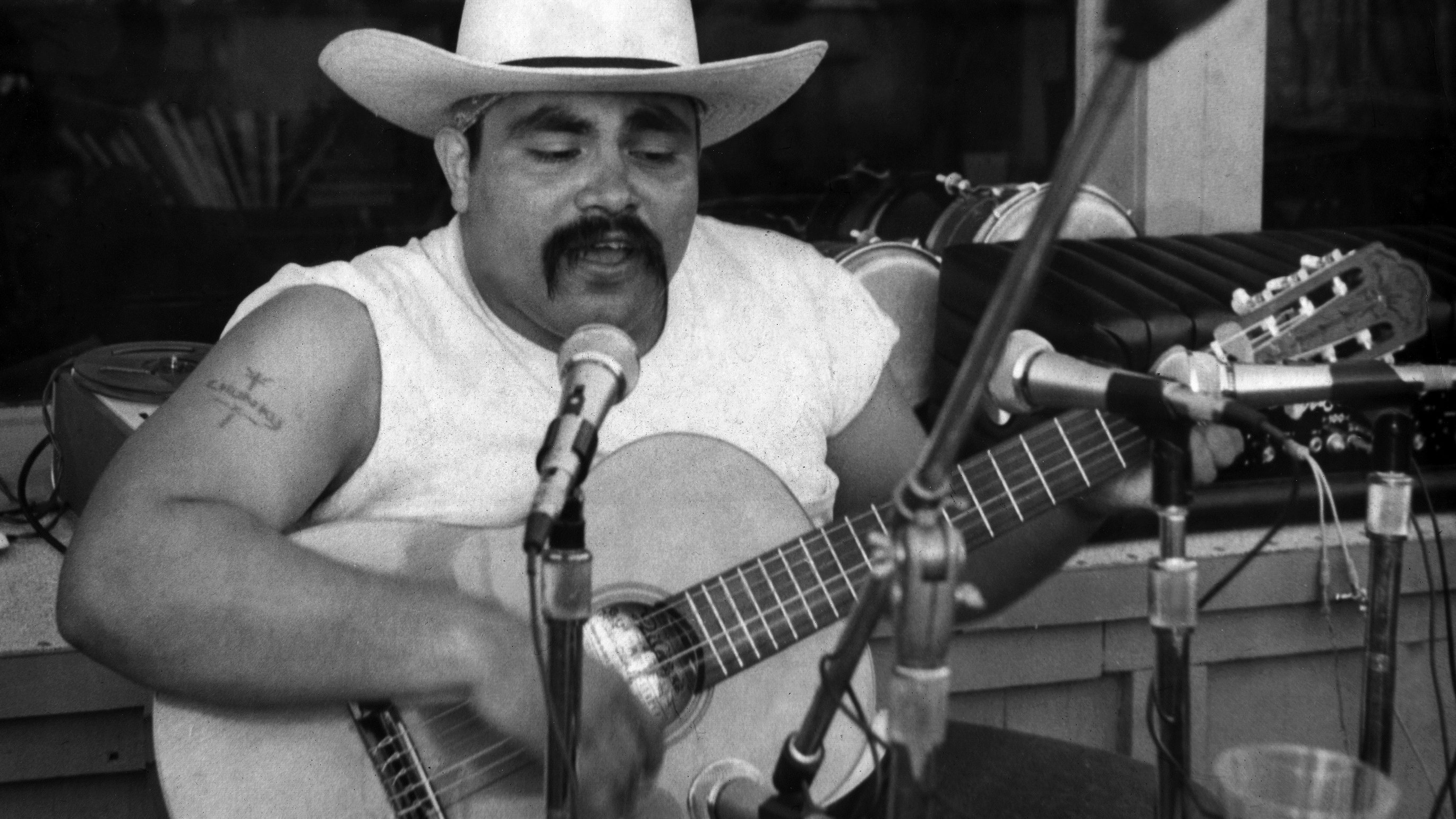 Ramon “Chunky” Sanchez singing with his guitar at microphone, ca 1974. Photo courtesy of Ramon “Chunky” Sanchez.